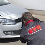 GTUe-Sachverstaendiger fotografiert einen Schaden am Fahrzeug mit Spiegelreflexkamera