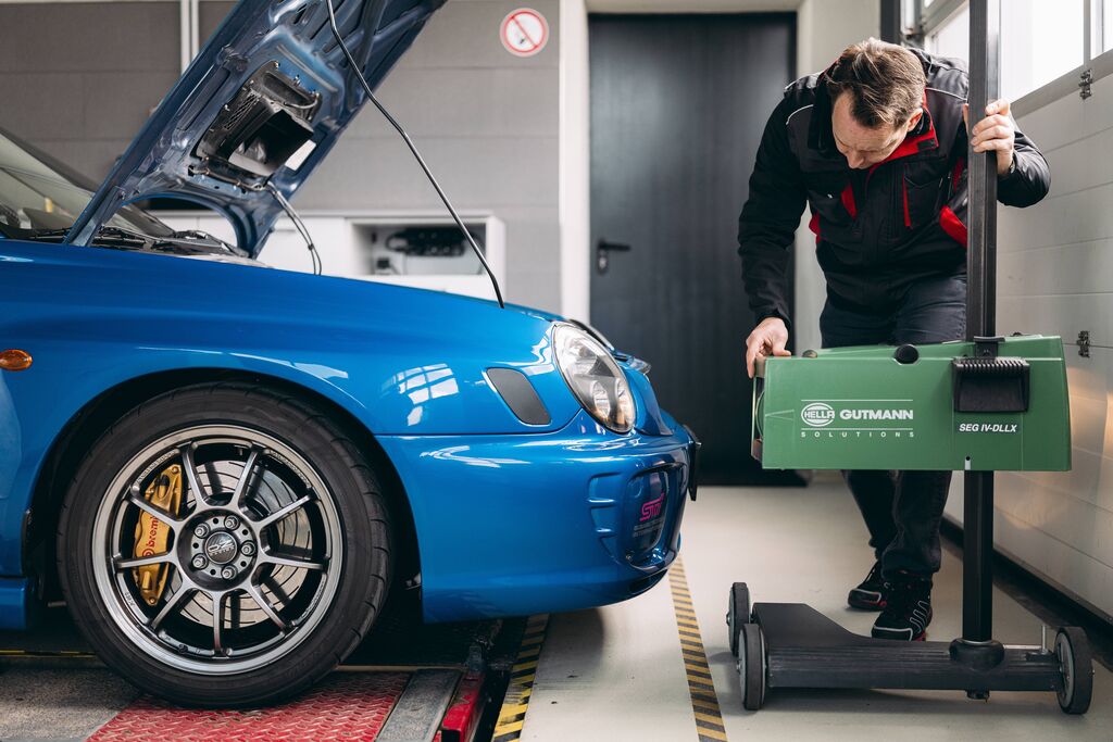 Prüfingenieur bei der Scheinwerfereinstellung an einem modifizierten Tuning-Fahrzeug
